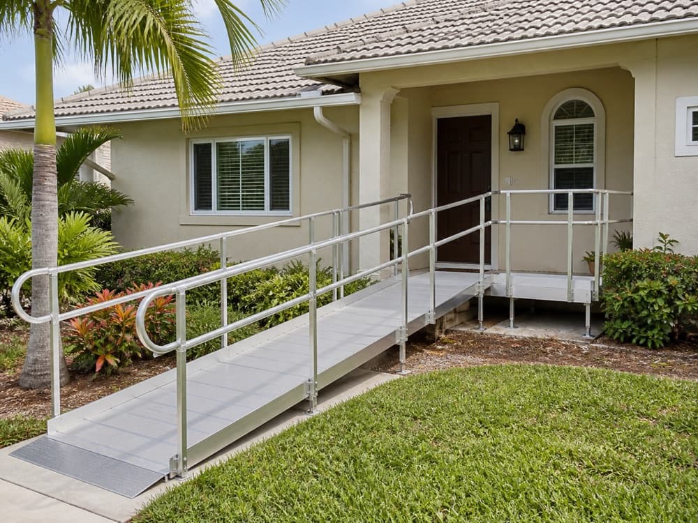 Modular aluminum wheelchair ramp with handrails and a level platform at a South Florida home